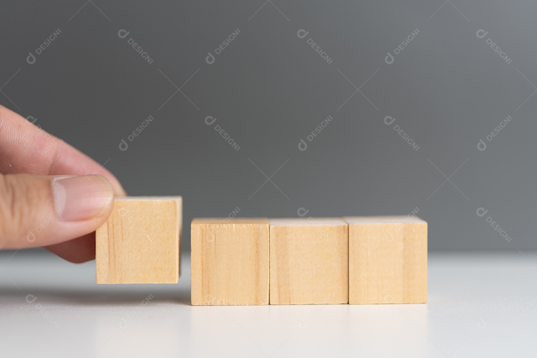 Mão segurando o bloco de madeira do cubo em branco no fundo.