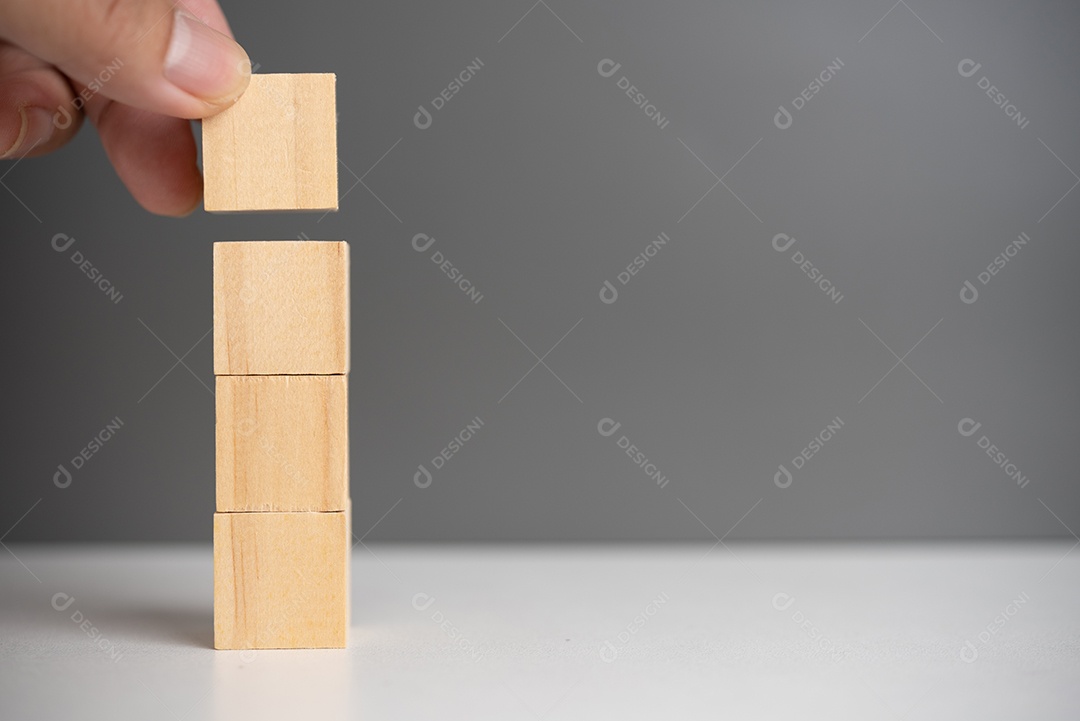 Mão segurando o bloco de madeira do cubo em branco no fundo.