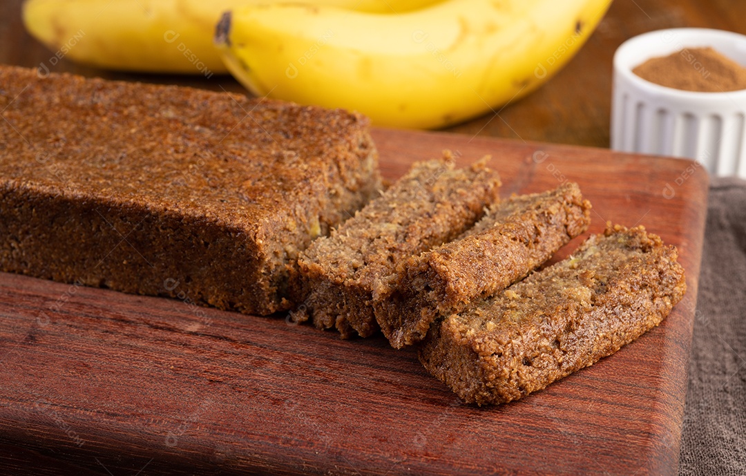 Grãos fatiados e bolo de banana sobre placa de madeira.