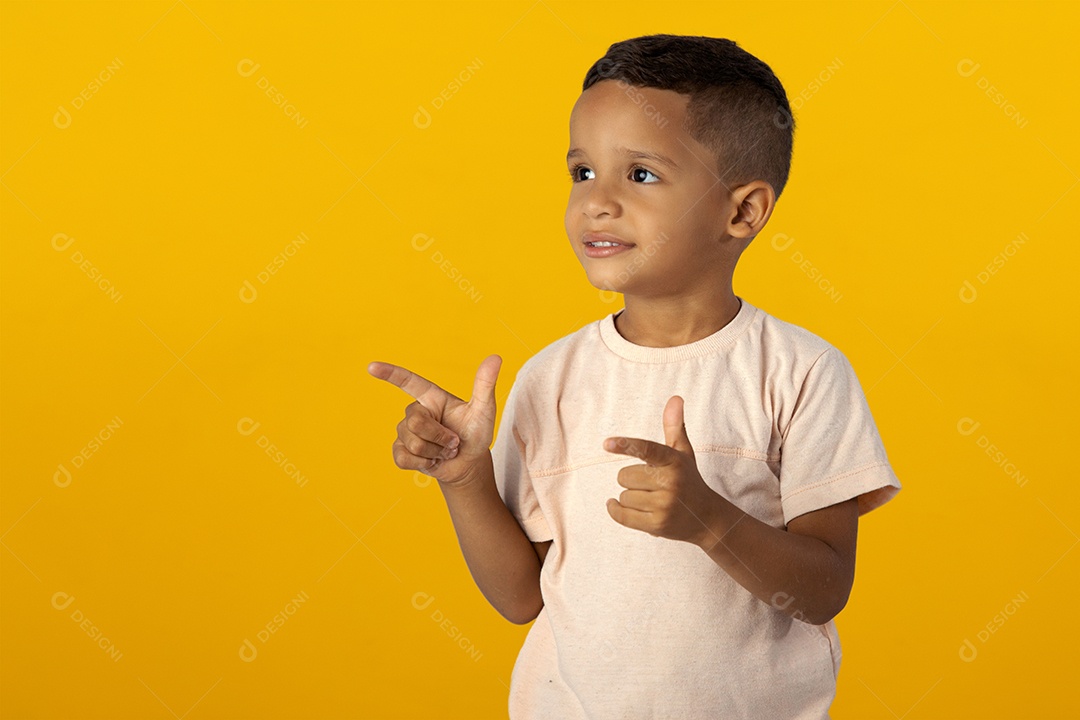 Menino de Camisa clara Sorrindo apontando para o lado isolado sobre fundo amarelo