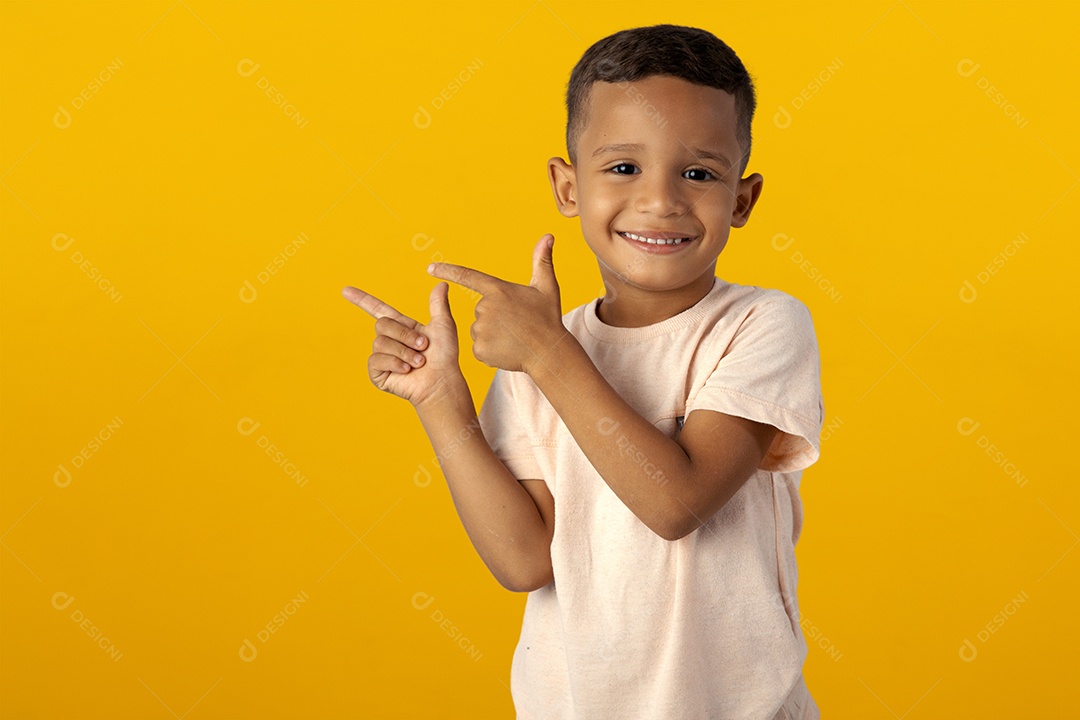 Menino de Camisa clara Sorrindo apontando para o lado isolado sobre fundo amarelo