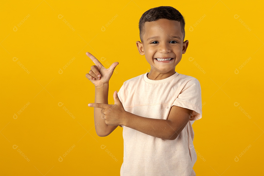 Boy in light shirt smiling pointing up and to the side isolated over yellow background
