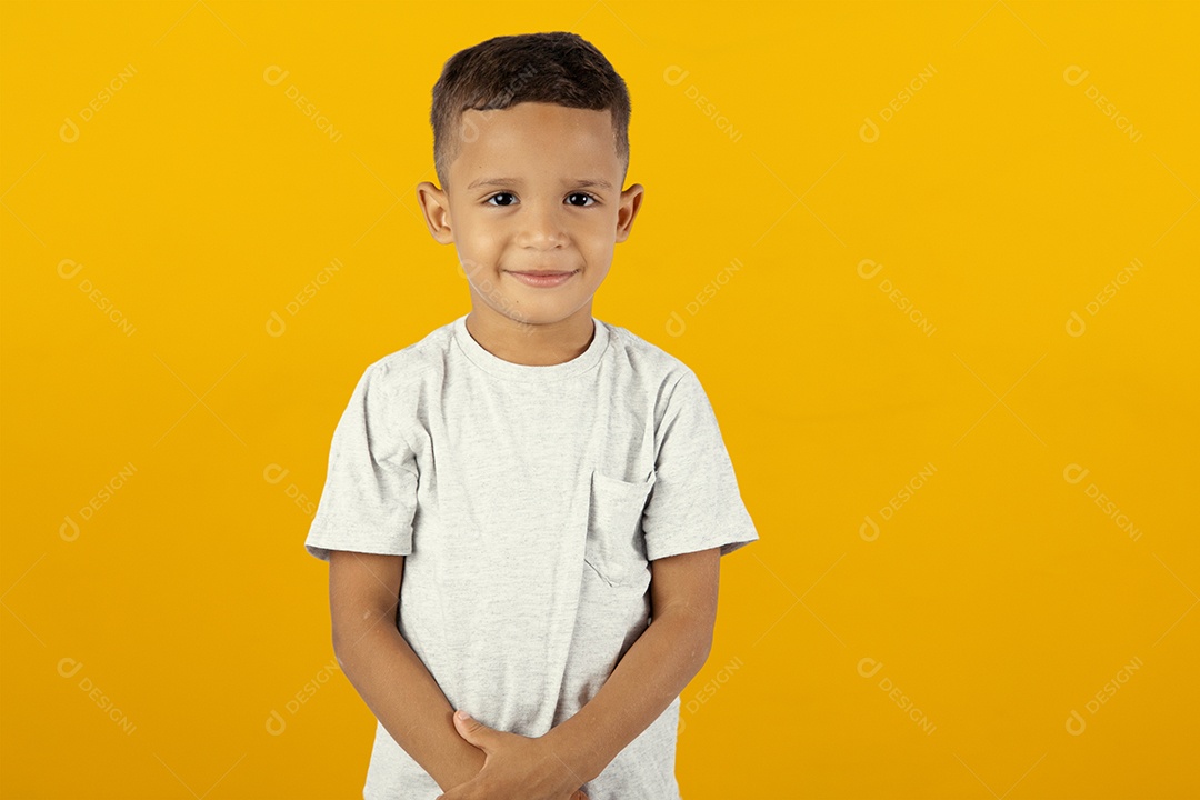 Menino feliz de camiseta cinza olhando para câmera isolado sobre fundo amarelo