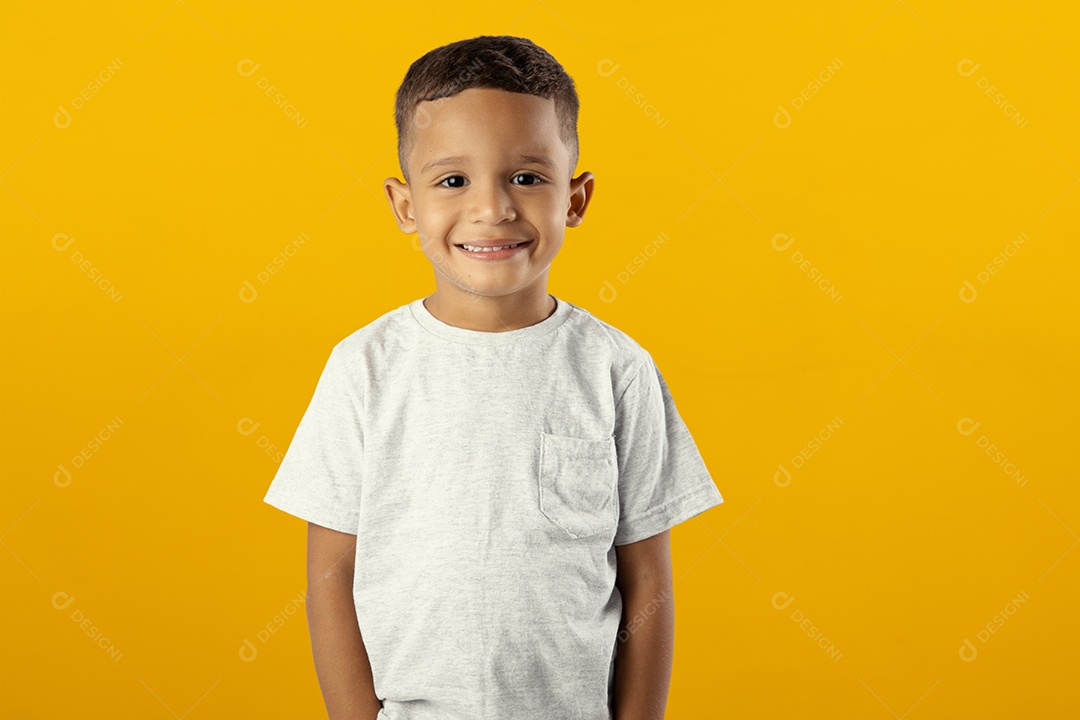 Menino sorridente olhando para câmera isolado sobre fundo amarelo