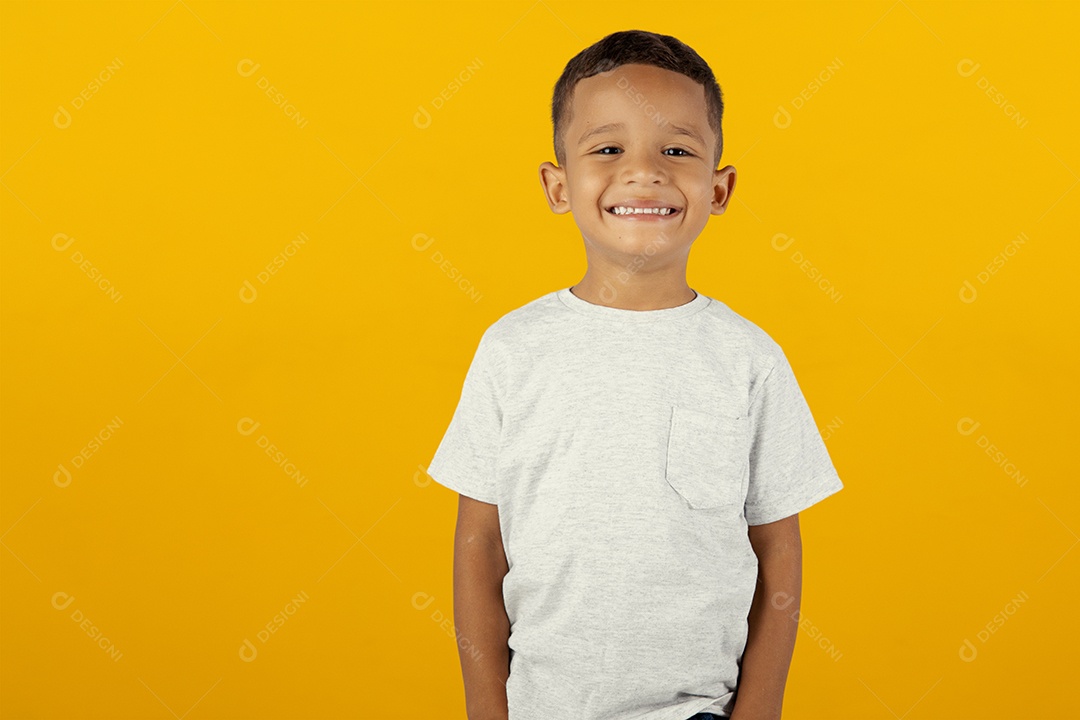 Menino de camiseta cinza feliz e sorridente ohando para câmera isolado sobre fundo amarelo