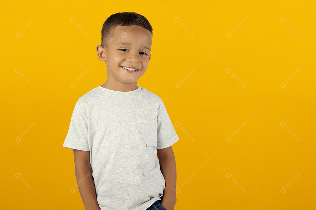 Criança de camiseta cinza sorridente com as mão no bolso