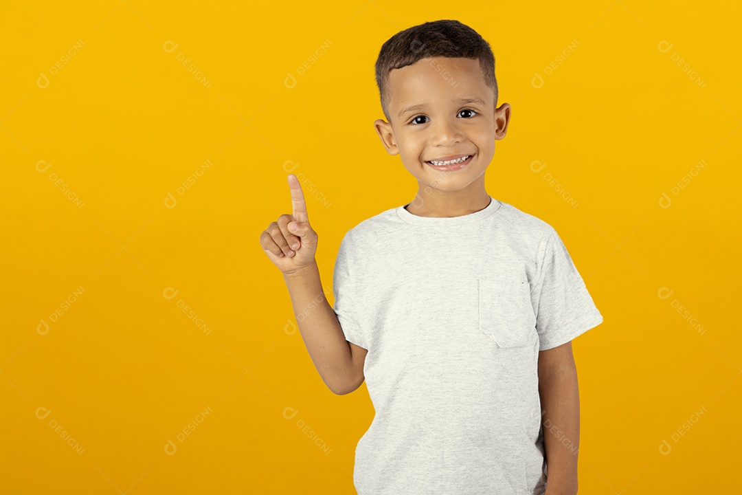 Menino sorridente apontando para o cima isolado sobre fundo amarelo