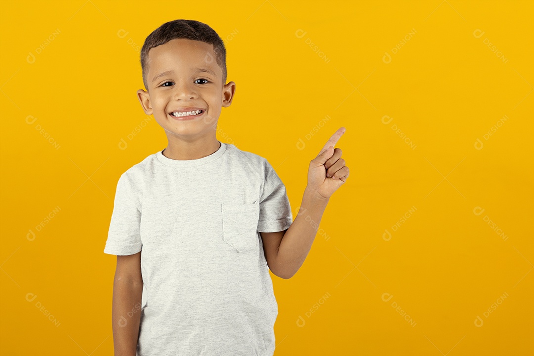 Menino sorridente apontando para o lado isolado sobre fundo amarelo