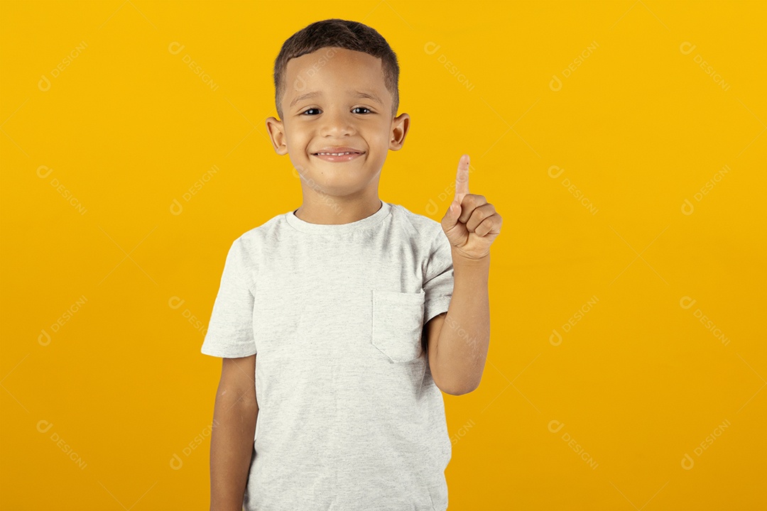Menino de camisa cinza sorrindo para câmera com polegar para cima isolado em fundo amarelo