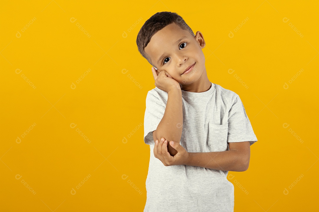 Menino sério tocando sua maçã do rosto isolado sobre fundo amarelo