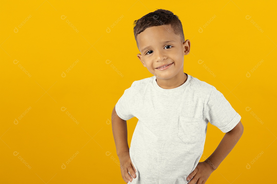 Jovem menino sorridente com a mão na cintura isolado sobre fundo amarelo