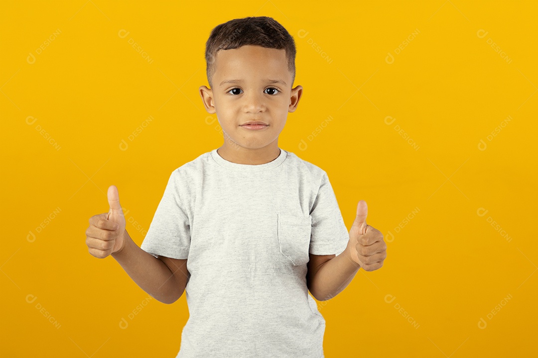 Jovem menino sério com os polegares para cima em fundo amarelo