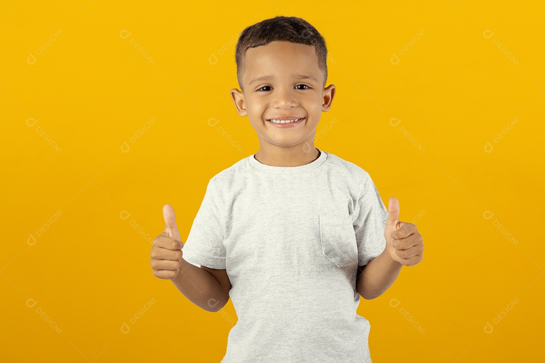 Menino feliz com os polegadores para cima isolado sobre fundo amarelo