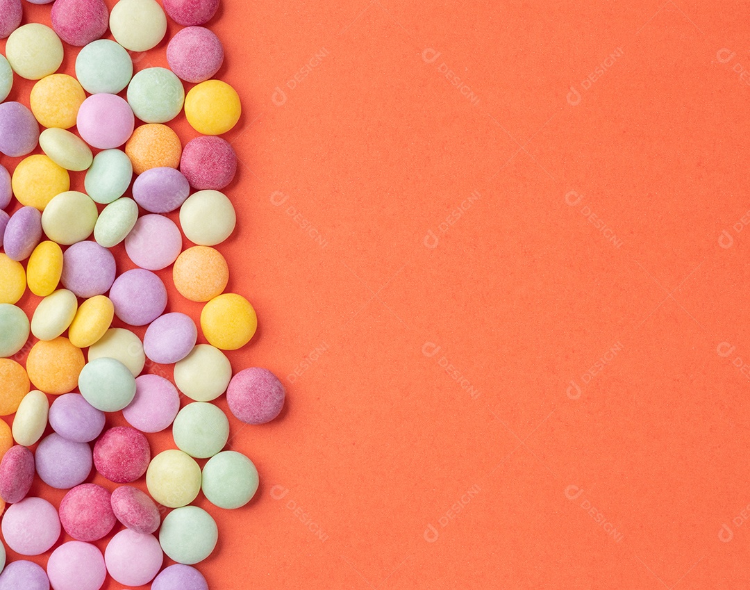 Quadro de doces coloridos sobre fundo laranja com espaço de cópia.