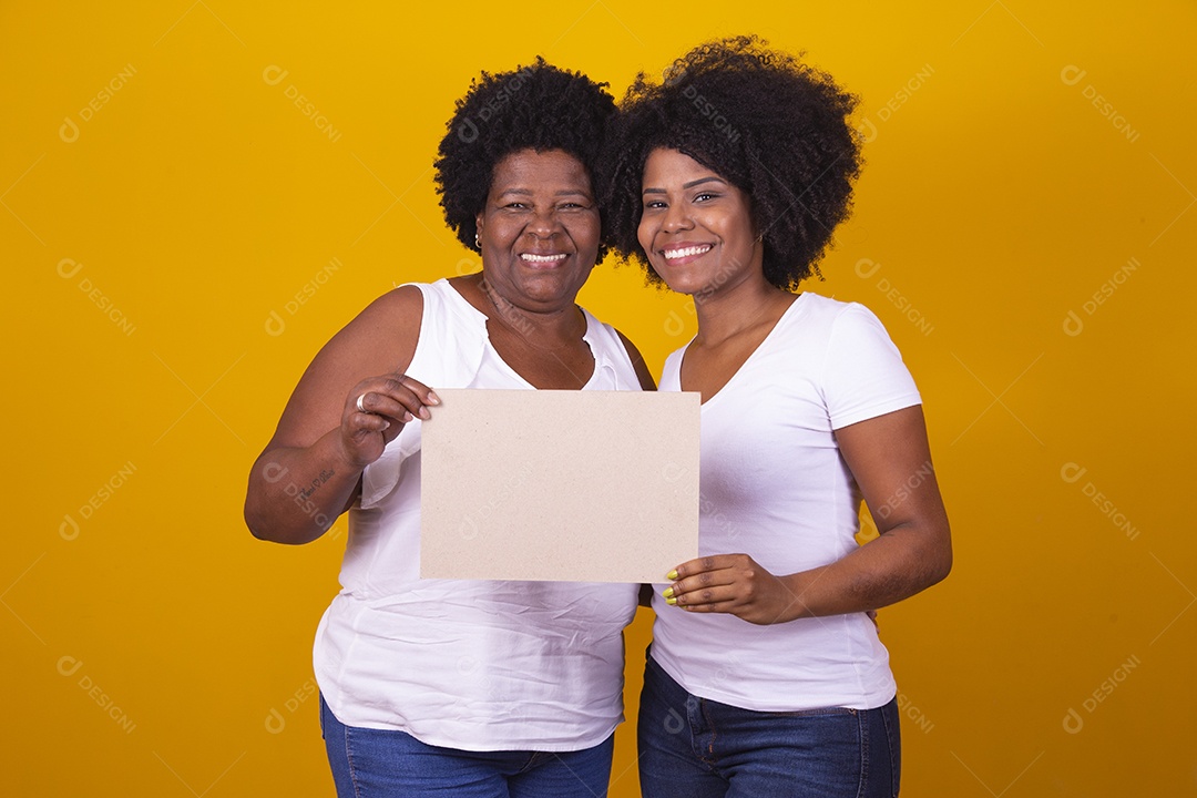 Mulheres negras mãe e filha vestidas com blusa branca com gestos de carinho segurando cartaz em branco