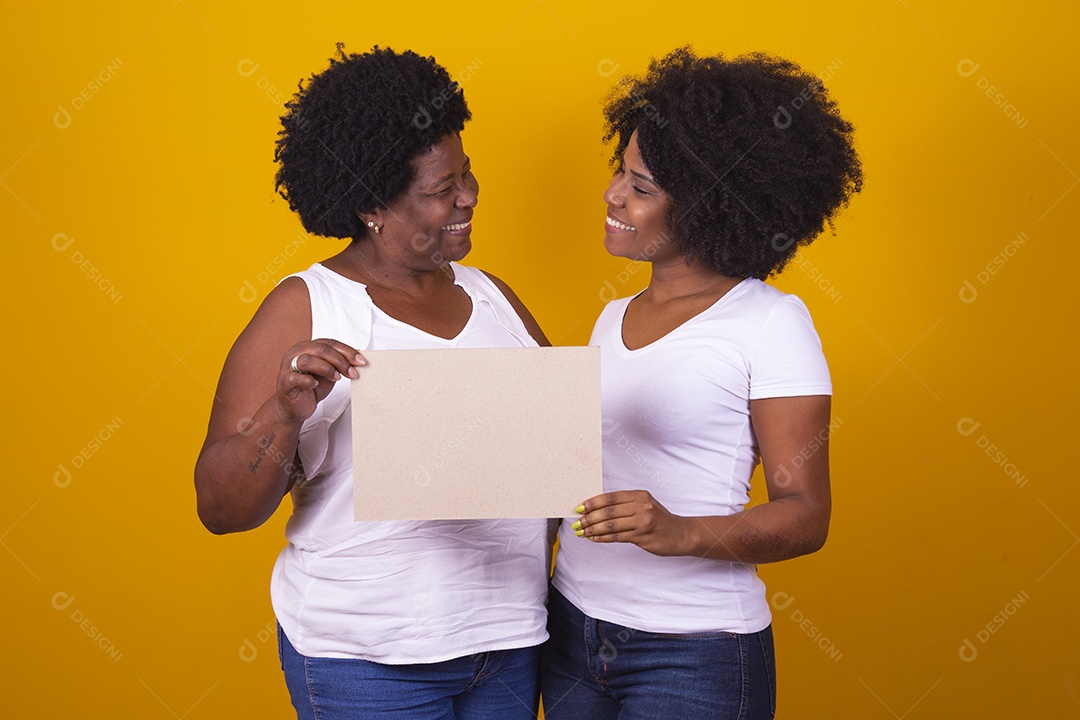 Mulheres negras mãe e filha vestidas com blusa branca com gestos de carinho segurando cartaz em branco