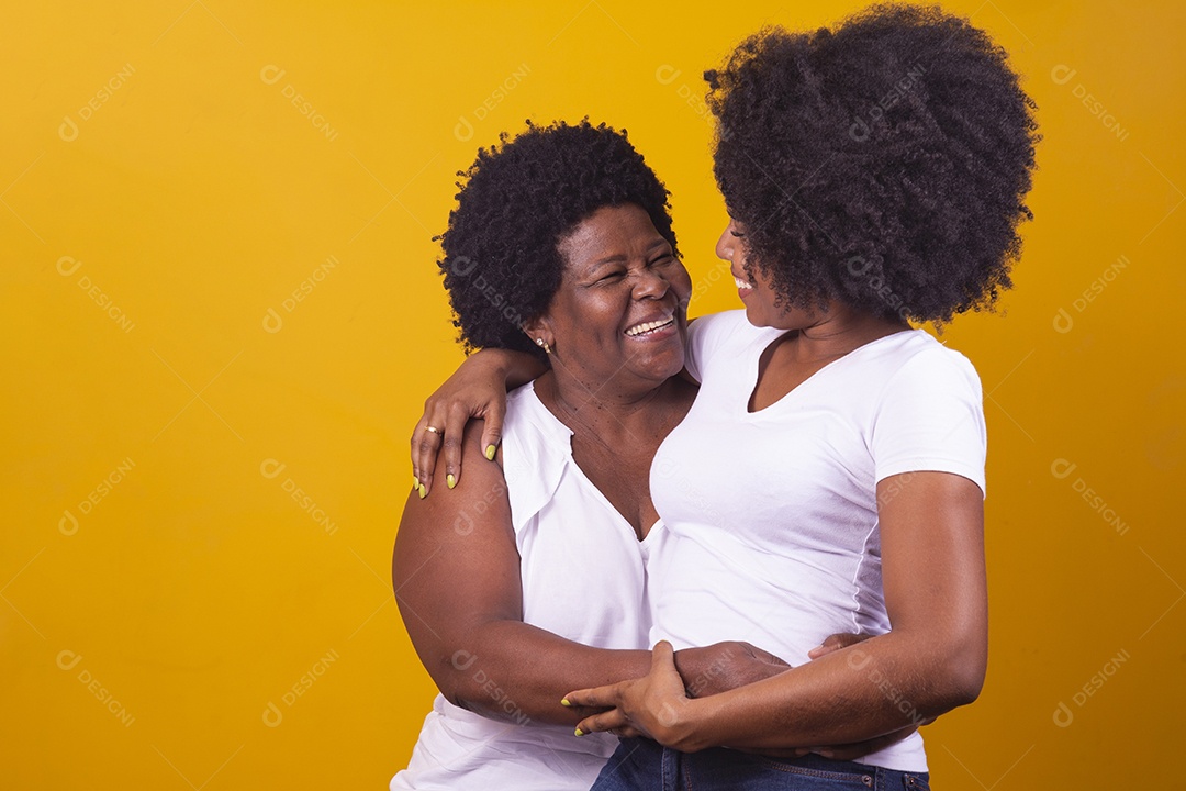 Mulheres negras mãe e filha vestidas com blusa branca abraçadas