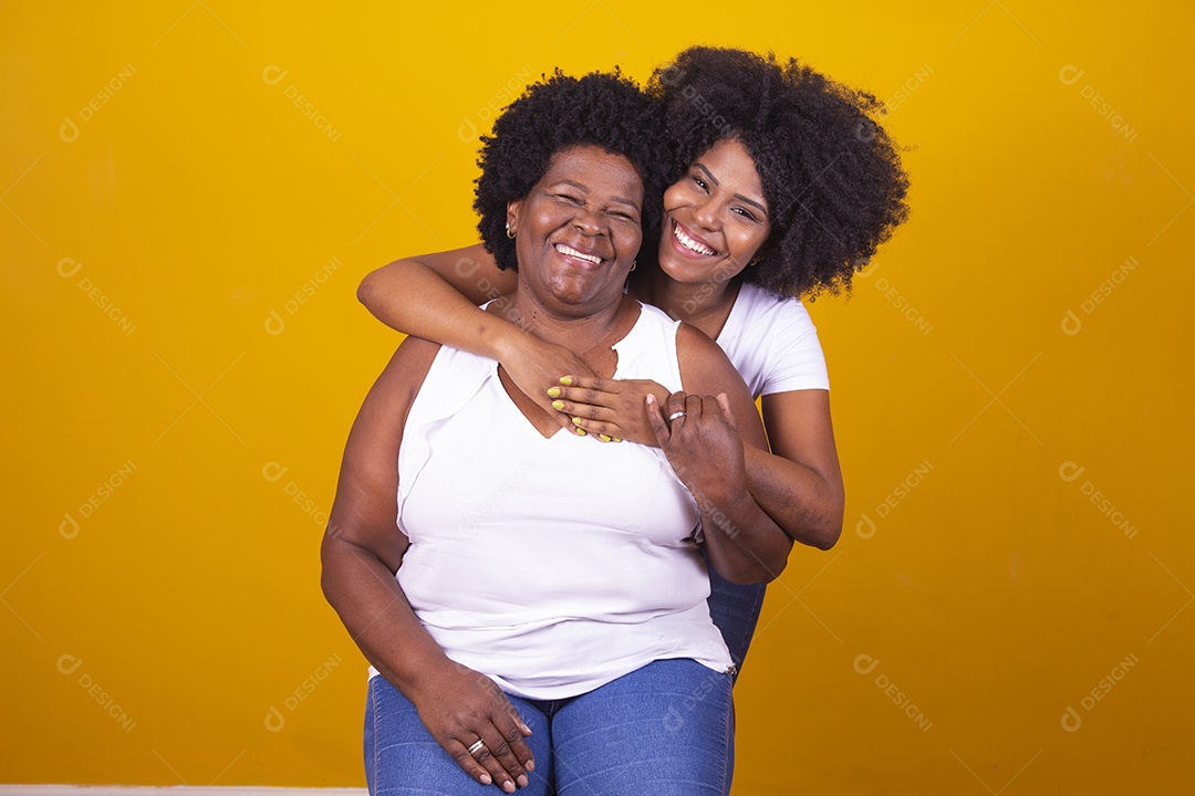 Mulheres negras mãe e filha vestidas com blusa branca abraçadas