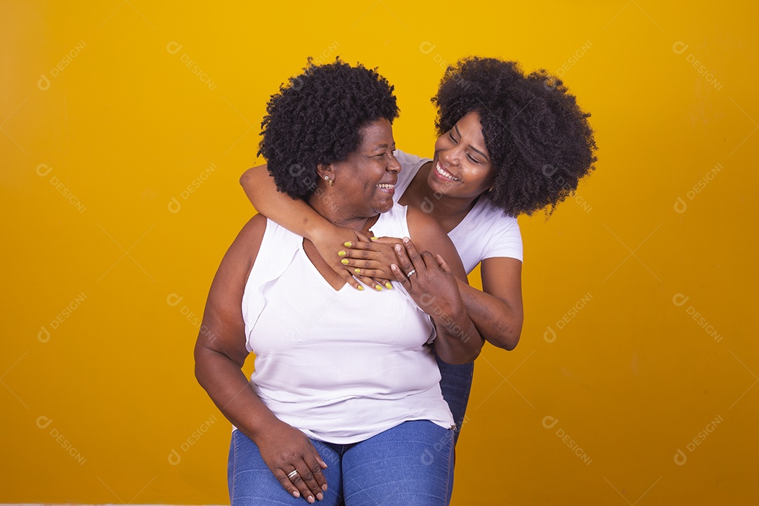 Mulheres negras mãe e filha vestidas com blusa branca abraçadas