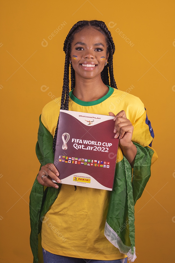 Mulher jovem torcedora segurando álbum de copa do mundo garota usando camiseta do brasil fundo isolado amarelo