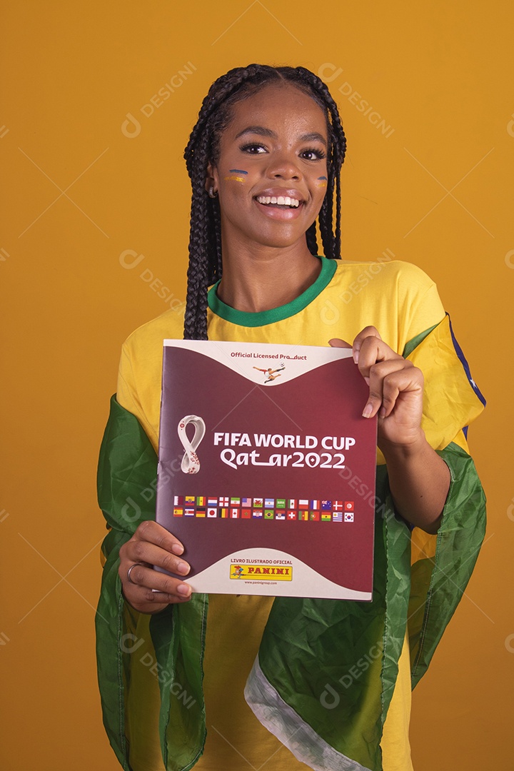 Mulher jovem torcedora segurando álbum de copa do mundo garota usando camiseta do brasil fundo isolado amarelo