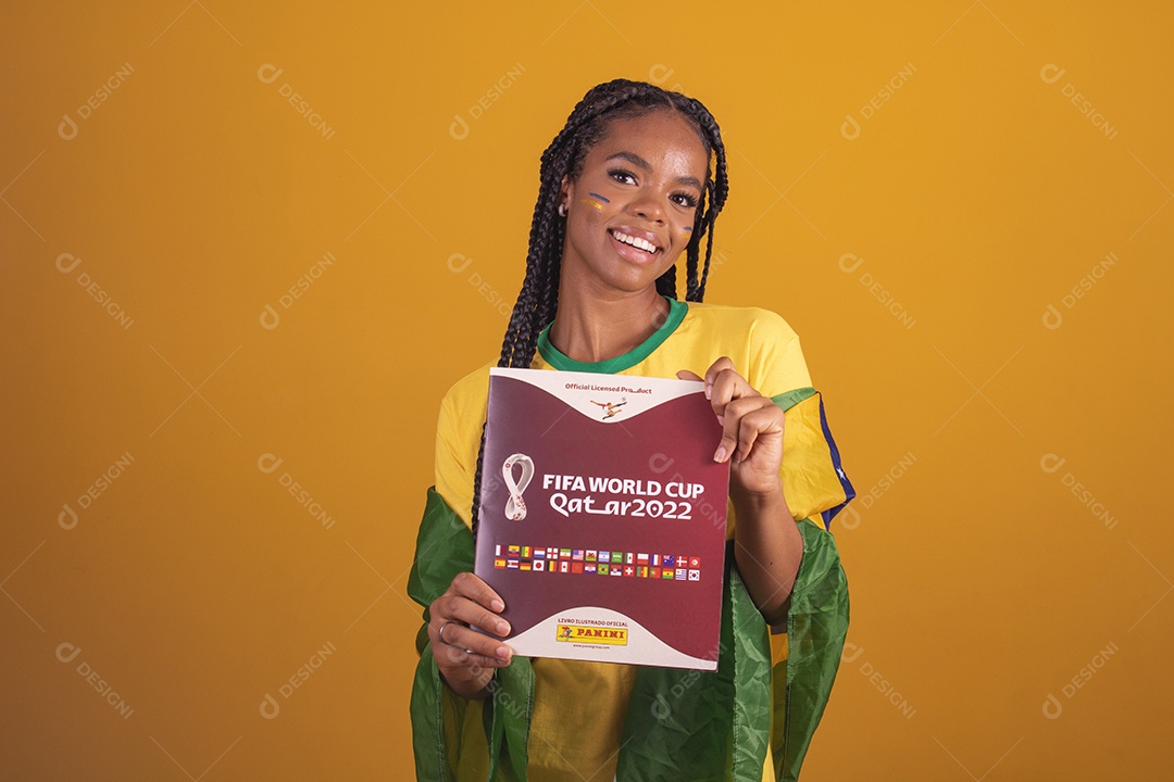 Mulher jovem torcedora segurando álbum de copa do mundo garota usando camiseta do brasil fundo isolado amarelo