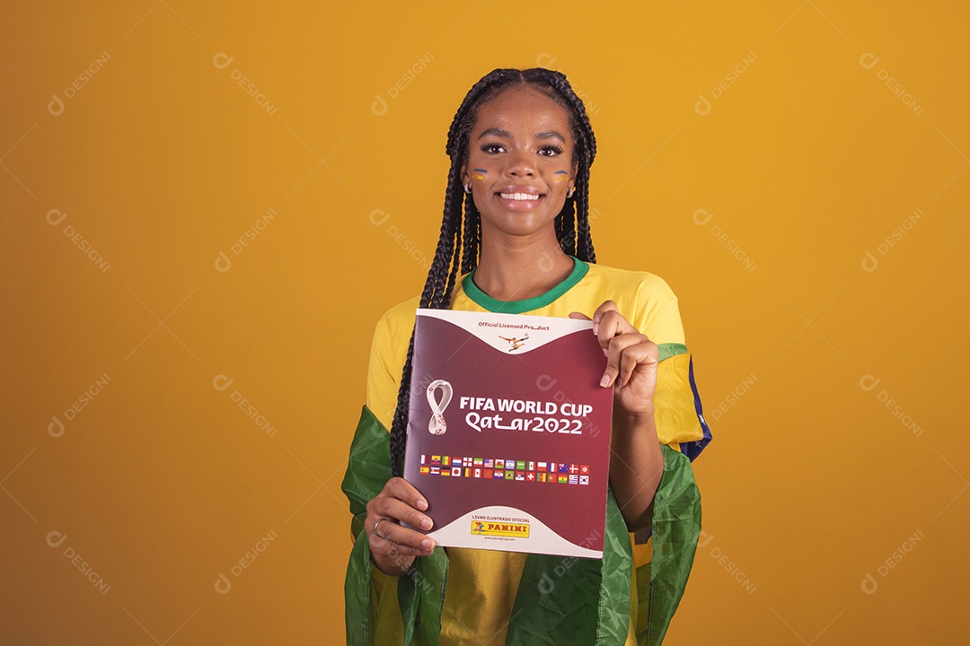 Mulher jovem torcedora segurando álbum de copa do mundo garota usando camiseta do brasil fundo isolado amarelo