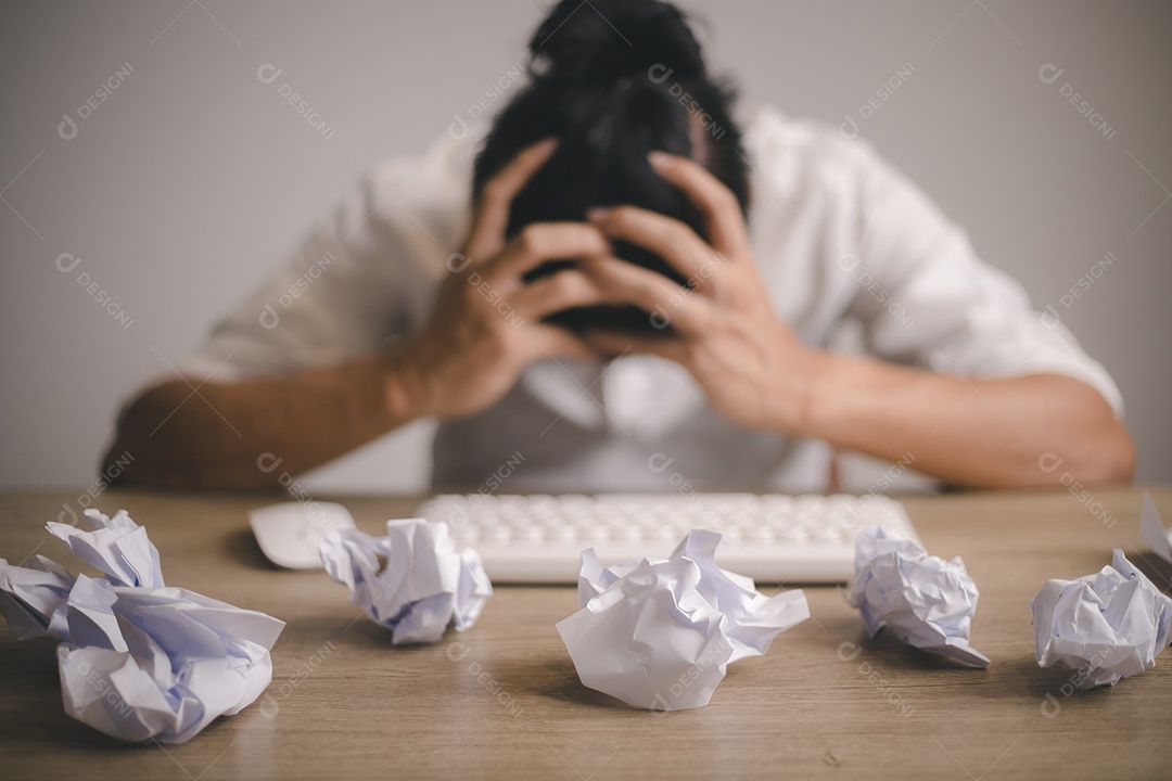 Empresário sentado com a cabeça nas mãos na mesa coberta amassada