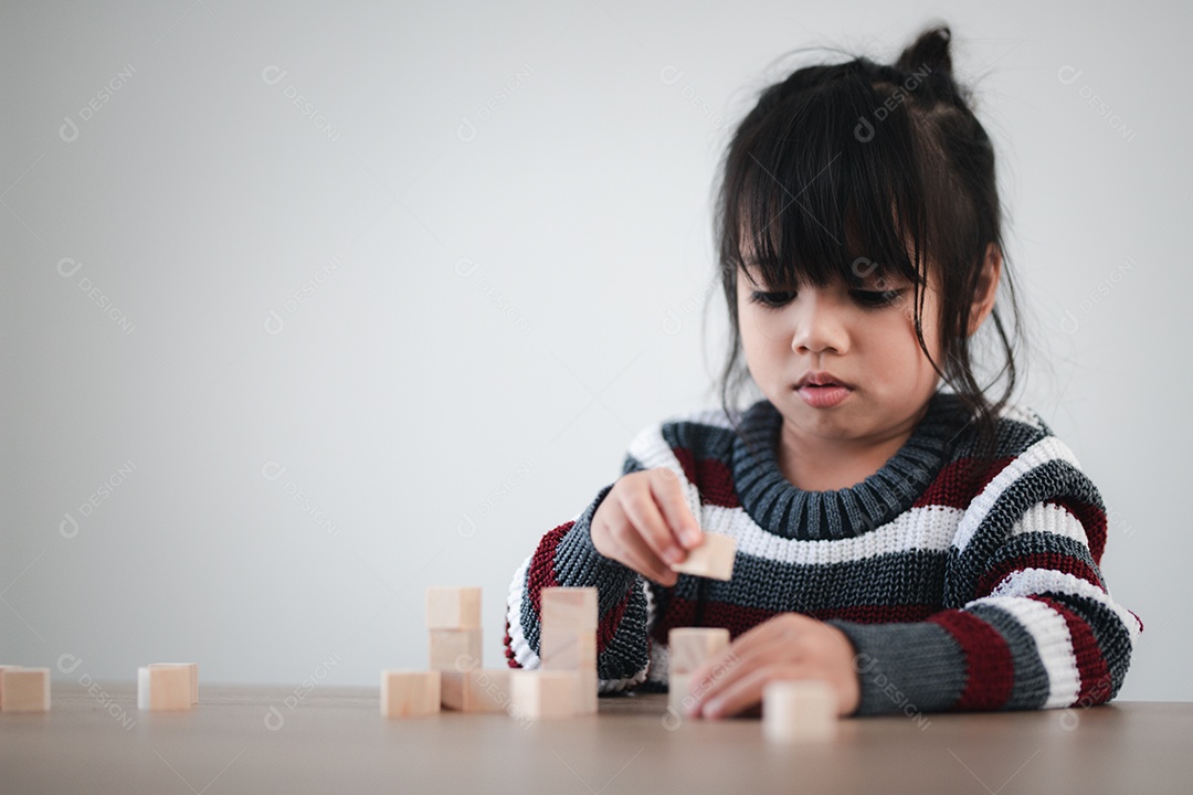 Alegre menina asiática brincando com blocos de madeira.