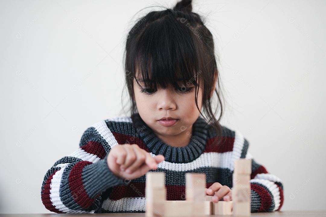 Alegre menina asiática brincando com blocos de madeira.