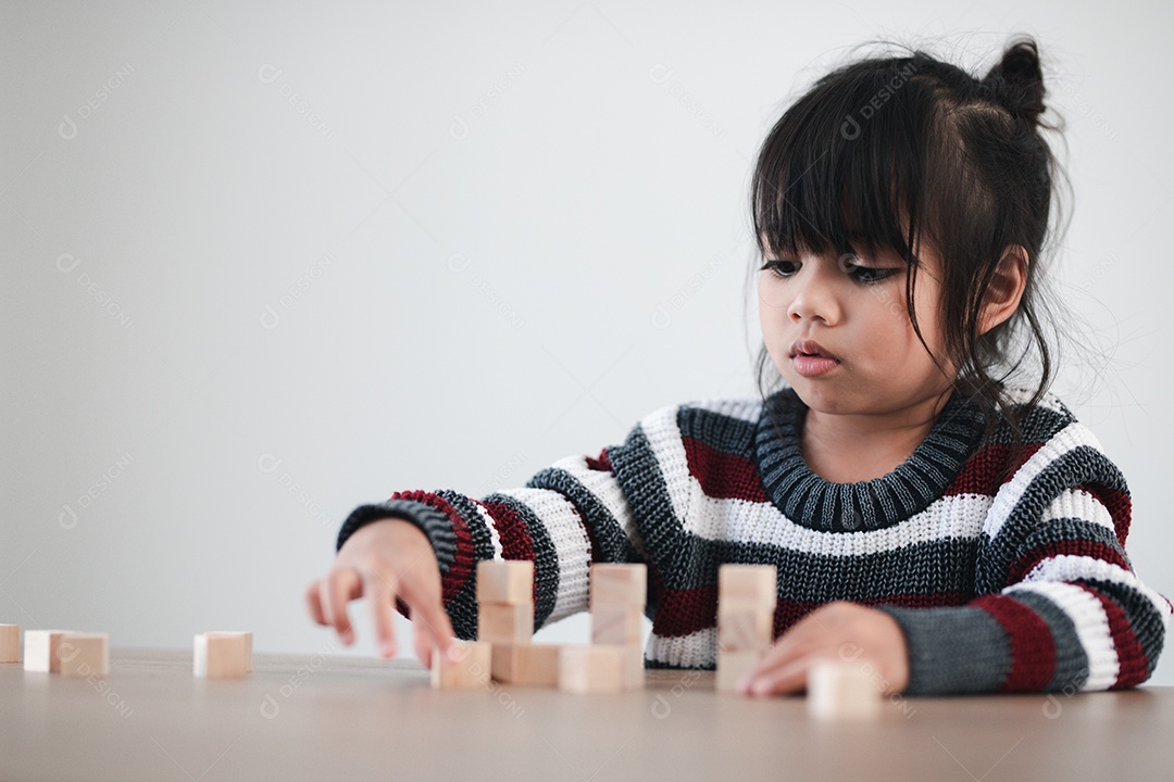 Alegre menina asiática brincando com blocos de madeira.