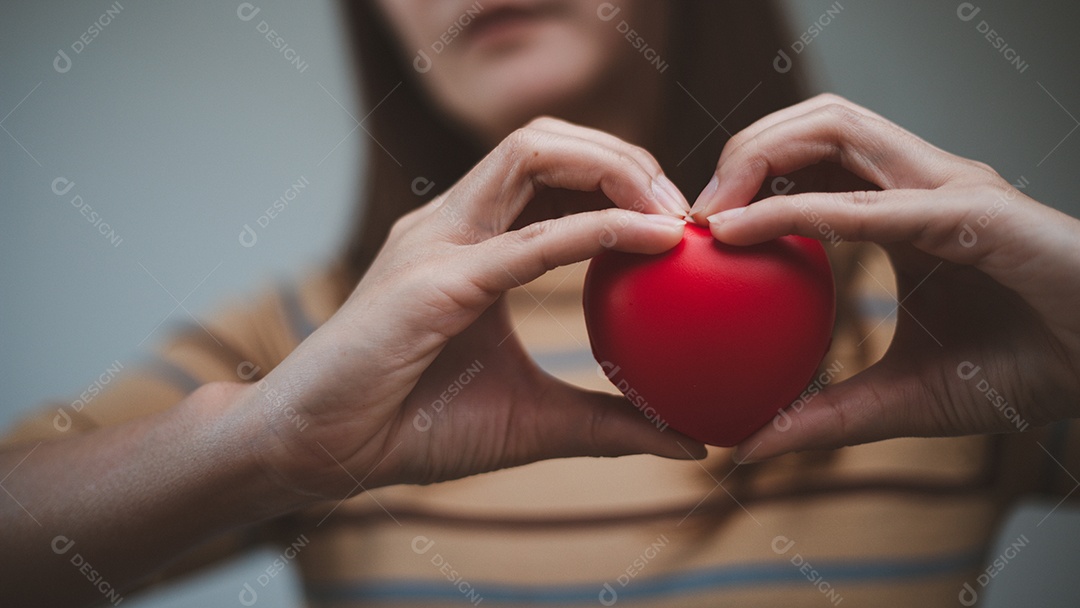 Mãos femininas segurando coração vermelho, dia mundial da saúde mental e mundo