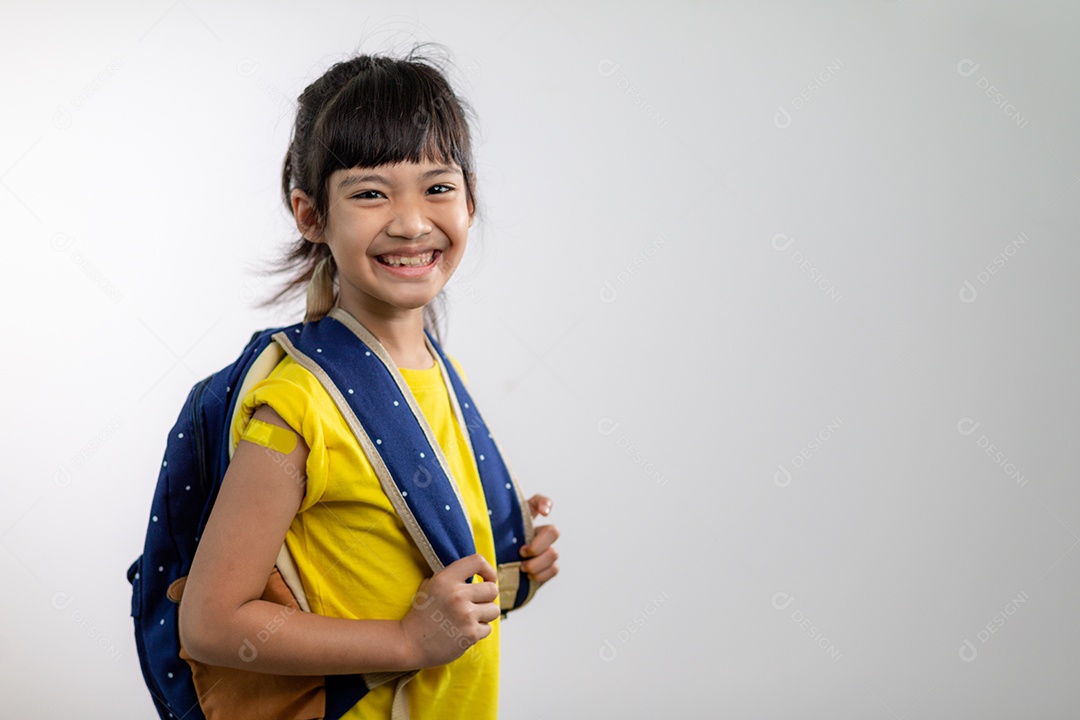 Menina asiática mostrando o braço com curativo amarelo