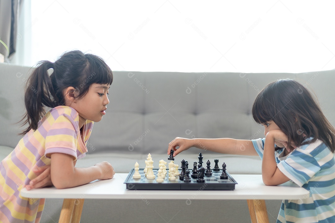 Irmas menina lindas jogando xadrez em casa.