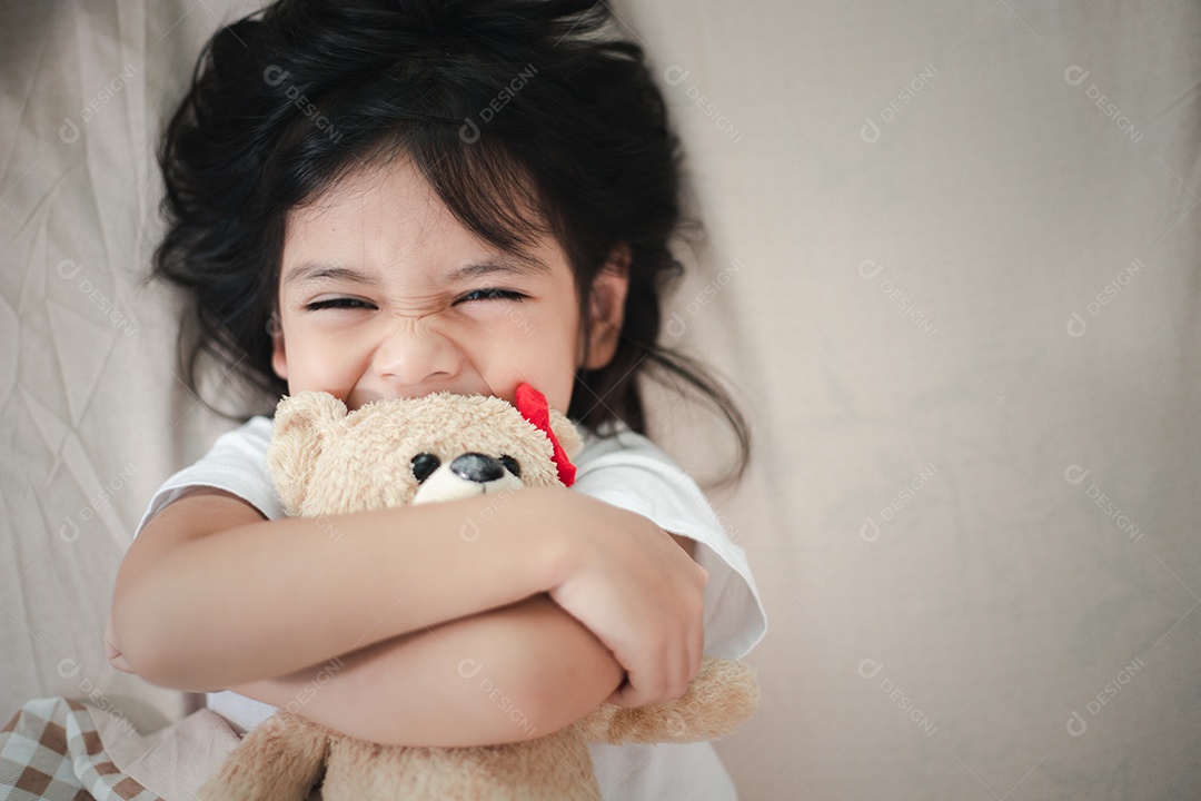 Criança menina dorme na cama com um ursinho de pelúcia de brinquedo