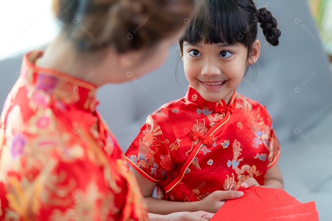 Menina asiática feliz recebeu envelope vermelho da mãe para o ano novo chinês