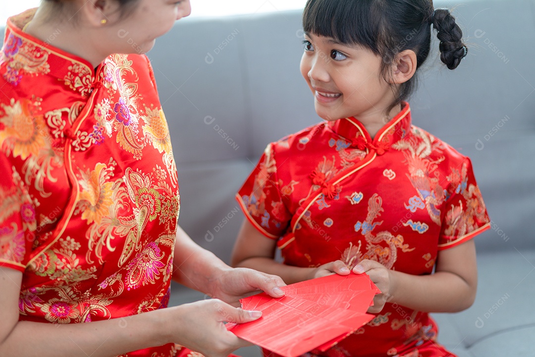 Menina asiática feliz recebeu envelope vermelho da mãe para o ano novo chinês