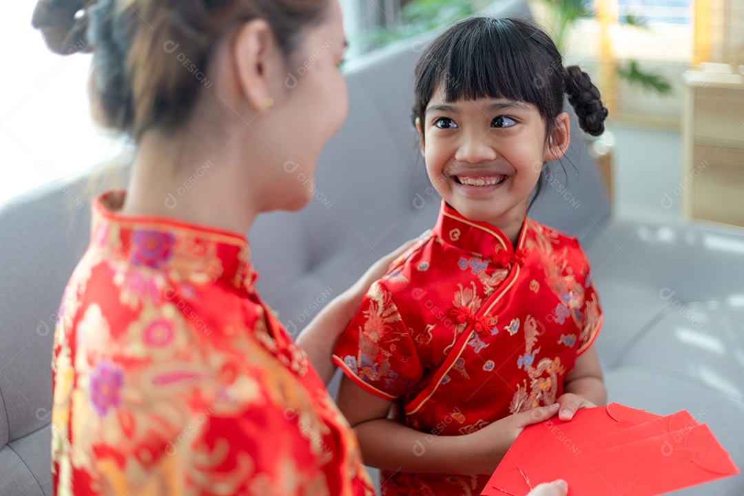 Menina asiática feliz recebeu envelope vermelho da mãe para o ano novo chinês
