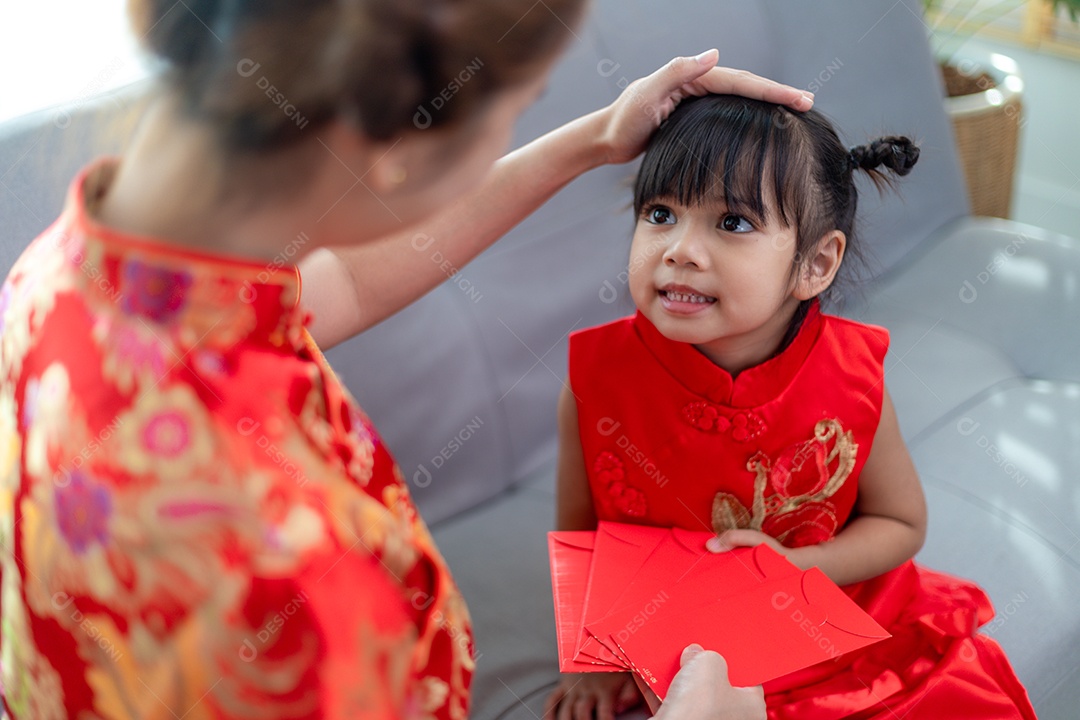 Menina asiática feliz recebeu envelope vermelho da mãe para o ano novo chinês