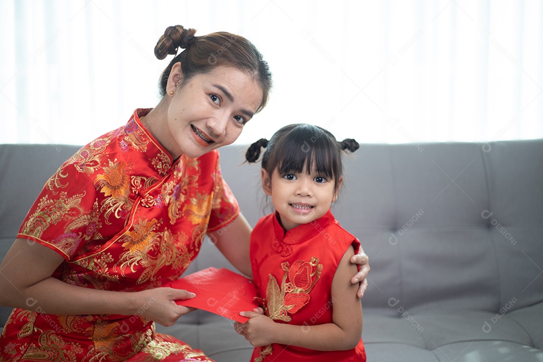 menina asiática feliz recebeu envelope vermelho da mãe para o ano novo chinês