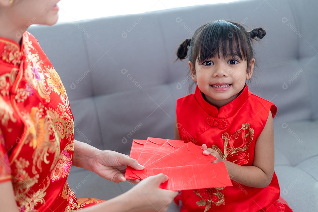 Menina asiática feliz recebeu envelope vermelho da mãe para o ano novo chinês