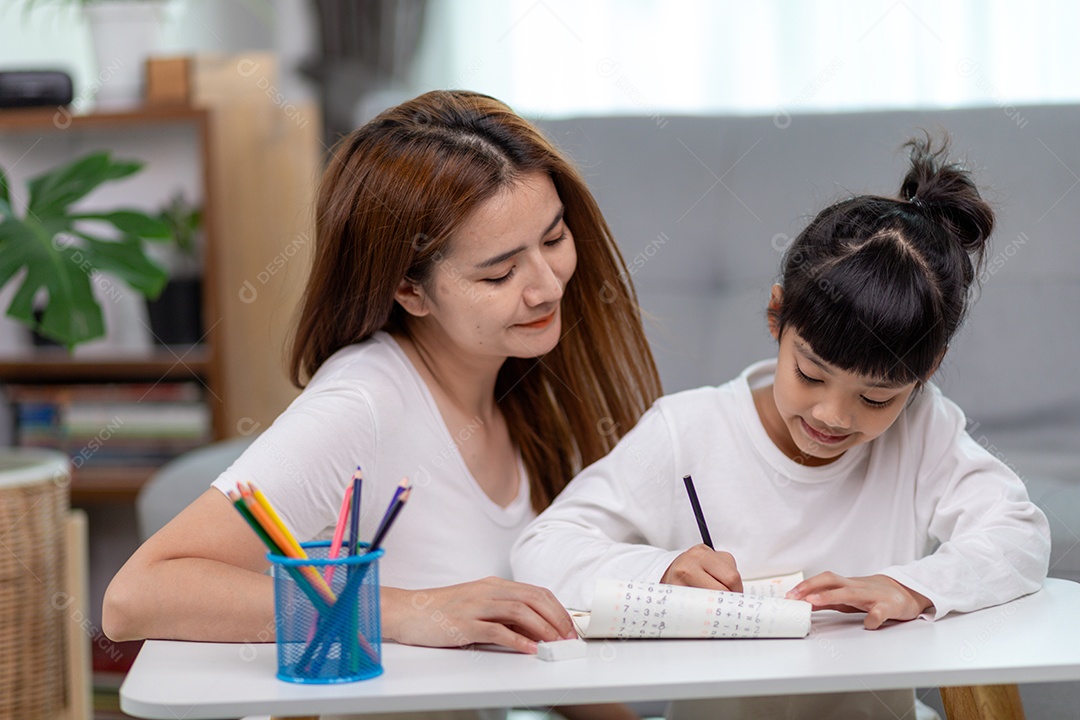 Linda mulher asiática ajudando sua filha com lição de casa em casa.