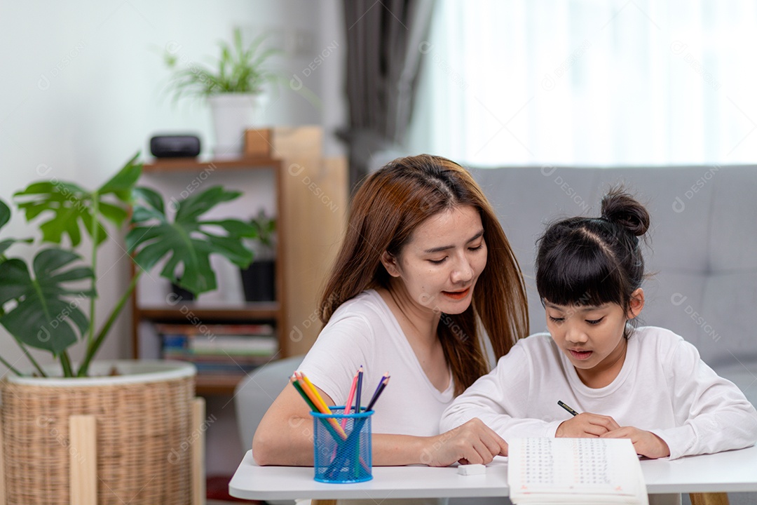 Linda mulher asiática ajudando sua filha com lição de casa em casa.