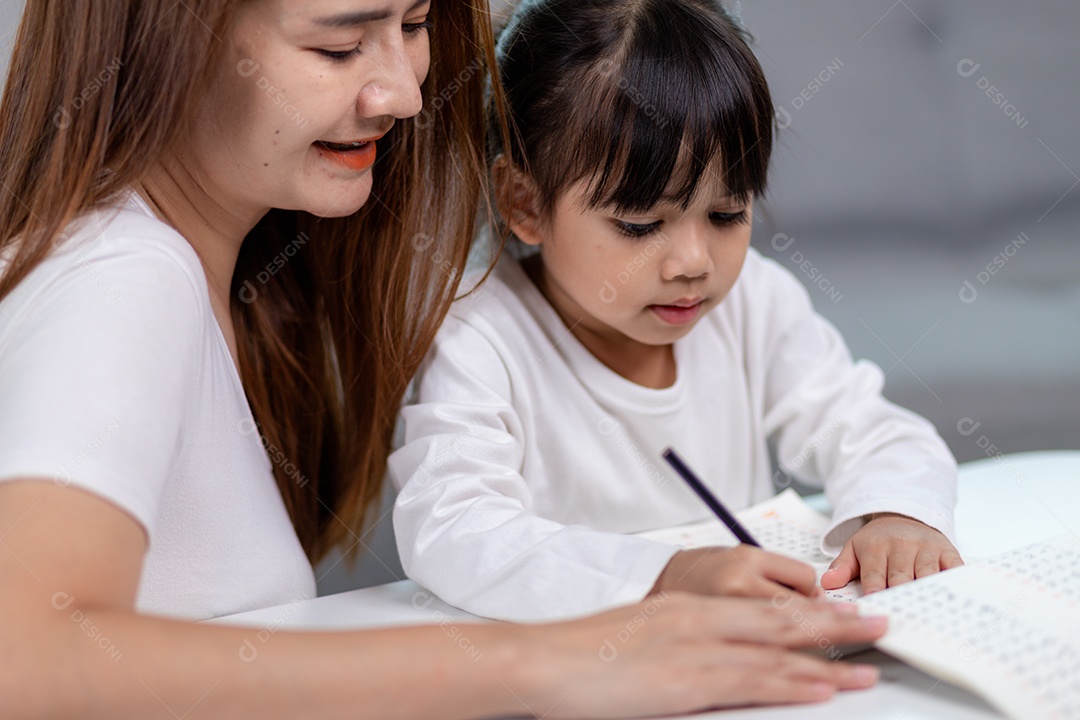 Linda mulher asiática ajudando sua filha com lição de casa em casa.