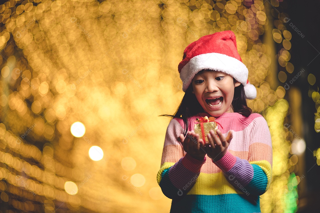 Criança feliz no chapéu vermelho de Papai Noel segurando presentes de Natal