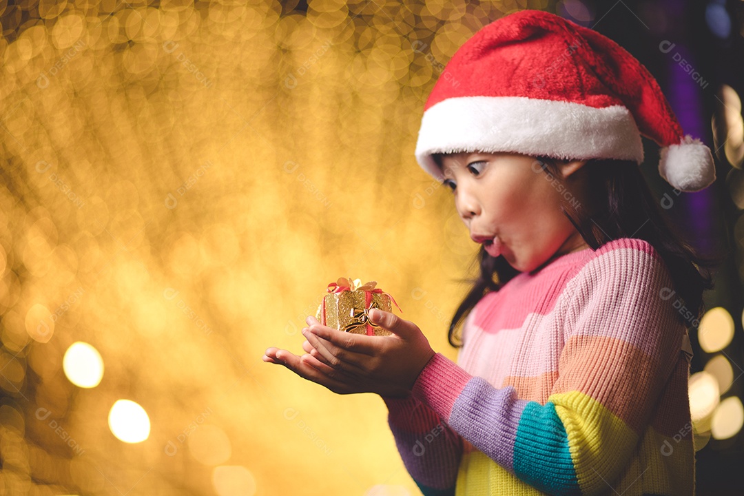 Criança feliz no chapéu vermelho de Papai Noel segurando presentes de Natal