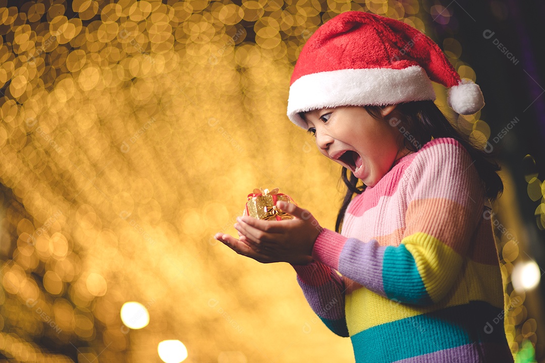 Criança feliz no chapéu vermelho de Papai Noel segurando presentes de Natal
