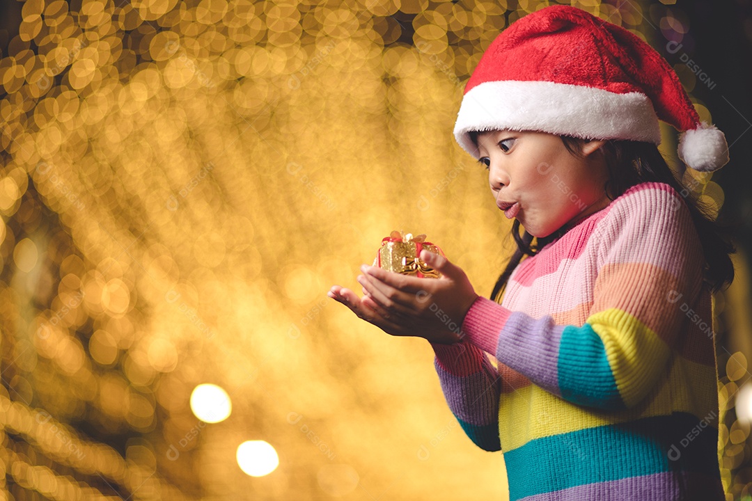 Criança feliz no chapéu vermelho de Papai Noel segurando presentes de Natal