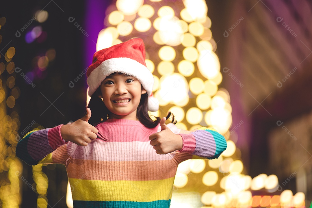 Criança feliz no chapéu vermelho de Papai Noel segurando presentes de Natal