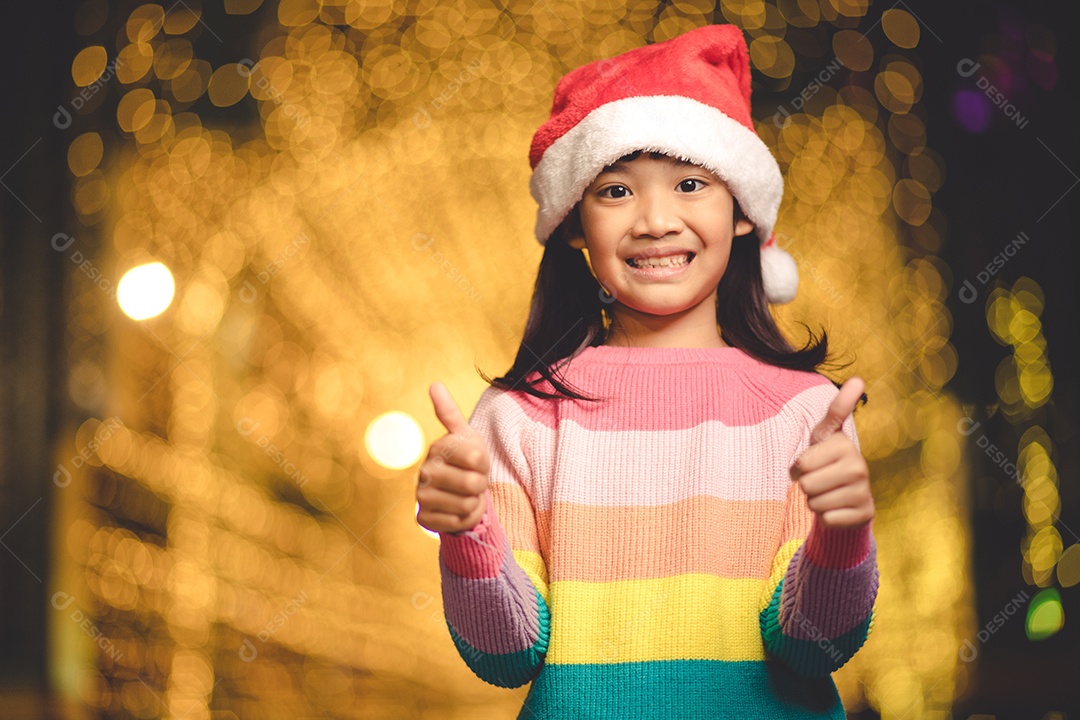 Criança feliz no chapéu vermelho de Papai Noel segurando presentes de Natal